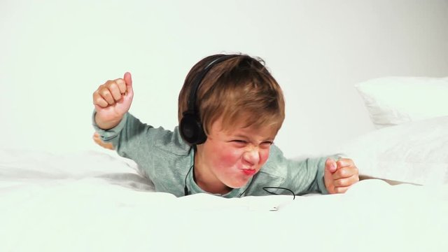 4 j&auml;hriger bub im bett mit kopfh&ouml;rern spielt mit dem tablet