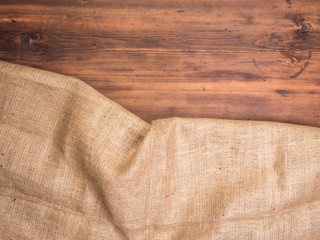 Old rural wooden table boards and burlap vintage background, photo top view. Hessian, sacking texture on wooden background for your design. Copy space for your message.