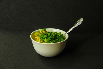 Plate with green vegetables soup on black background.