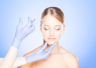 Doctor injecting in a beautiful face of a young woman. Plastic surgery concept.