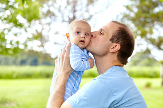 Portrait of young father kissing his newborn son