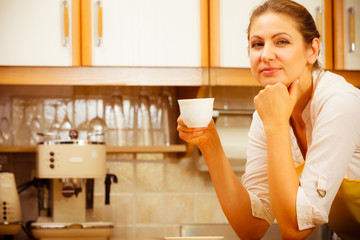 Obraz na płótnie Canvas Mature woman holding cup of coffee in kitchen.