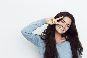 Fototapeta premium Beautiful woman with peace sign, smiling