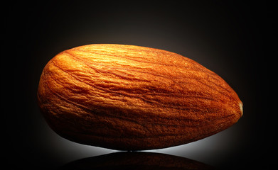 Almond on black background with reflection. Close-up or macro. Health concept