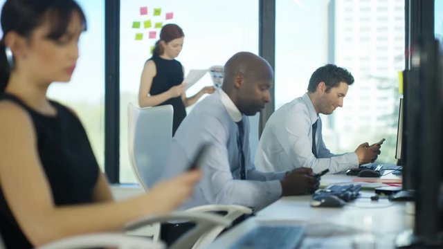  Bored business team in city office using cell phones for personal use