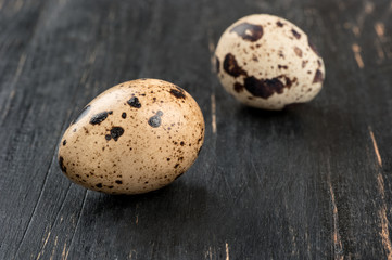 Fototapeta premium Two fresh quail eggs on a dark wooden background