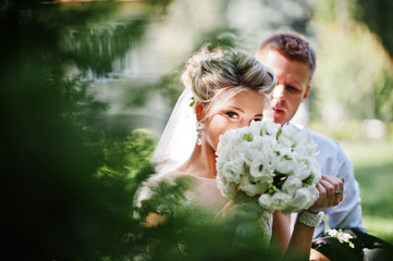 Stylish and gorgeous wedding couple walking outdoor at park on sunny weather.