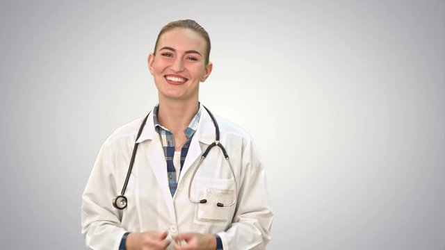 Smiling beautiful woman in lab coat talking to the camera on white background.