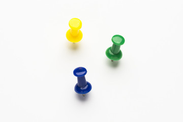 Three colored push pins on white background