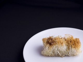 Traditional greek and turkish pastry cake named kadaif or kataifi isolated on black background
