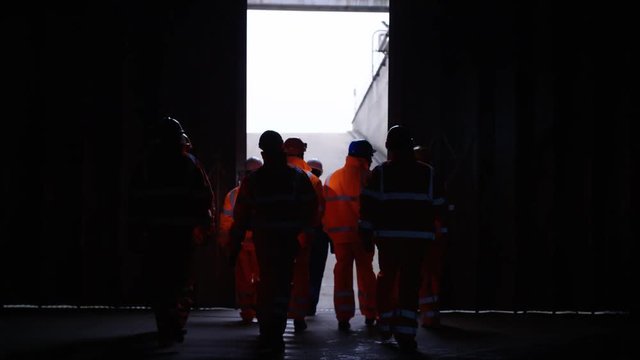  Workers at a fuel plant walking into darkness & preparing to go underground