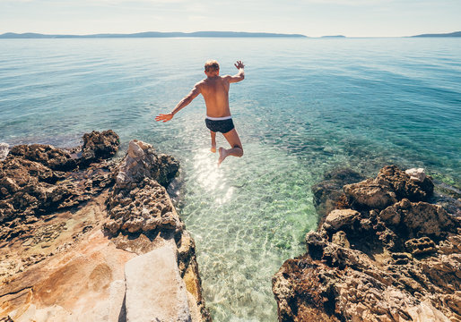 Man jumps in blue sea lagune water