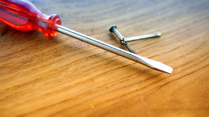 screwdriver and screws on wooden board.