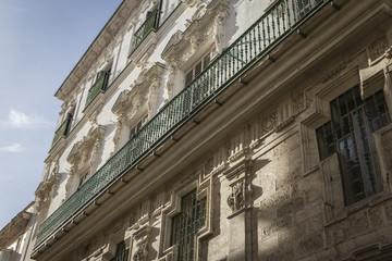 Fototapeta na wymiar Detail of balconies and large windows on the time of the nineteenth century, Narrow street with traditional architecture in Cadiz, Andalusia, southern Spain