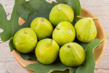 Ripe fresh green figs on wooden plate