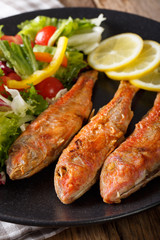 Roasted red mullet with fresh vegetables and lemon close-up. Vertical