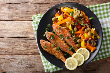 Roasted red mullet with stewed vegetables, lemon and greens close-up. horizontal top view
