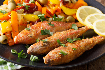 Fried mullet with stewed vegetables and lemon close-up. horizontal