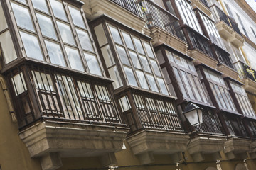 Obraz premium Detail of balconies and large windows on the time of the nineteenth century, Narrow street with traditional architecture in Cadiz, Andalusia, southern Spain