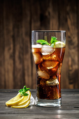 Beautiful glass with cola with lemon, ice and mint