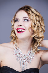 Portrait d'une jeune femme souriante  en robe de soirée, de trois quart, la main derrière la...