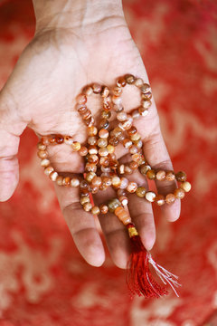 Mala of Buddhist prayer in red and white semi-precious stone and hand offering