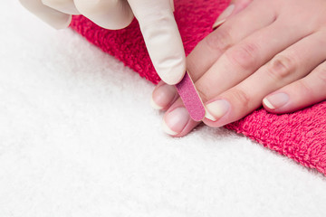 Hands in gloves cares about hands nails. Manicure beauty salon. Nails filing with file.