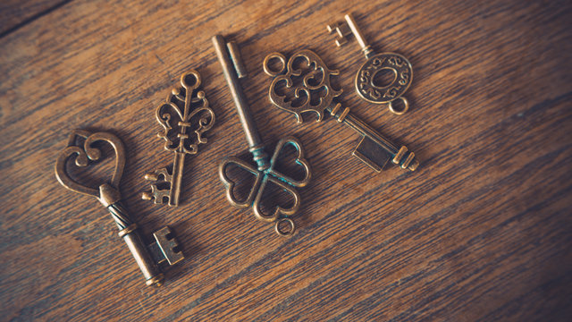 Antique skeleton padlock and retro lock keys on wooden texture background.