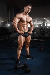 Fototapeta na wymiar Portrait of a handsome muscular bodybuilder posing in gym