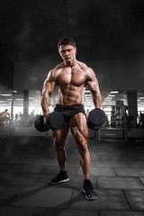 Fototapeta na wymiar Athlete muscular bodybuilder man demonstrates his muscles in the gym