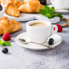 Healthy breakfast with coffee, croissants, fresh berries and orange juice on light gray background, selective focus, copy space.