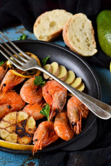 Fried tiger shrimps with garlic and lemon sauce on a cast-iron frying pan