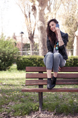 girl on a bench in a urban park using a smartphone and smiling