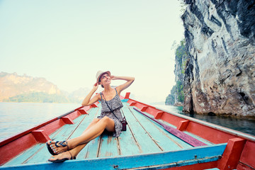 Obraz premium Happy vacation in Thailand. Pretty young woman taking sailing Khao Sok National Park lake on traditional longtail boat.