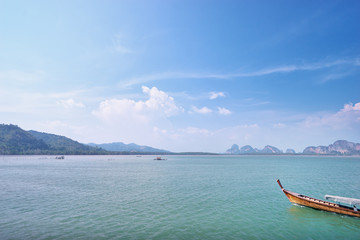 Beautiful seascape with traditional thai longtail boat and rocks on horizon.