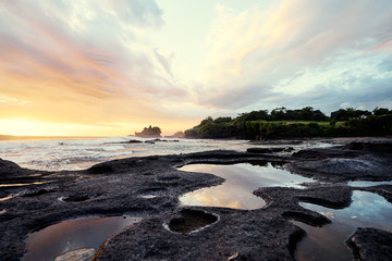 Obraz premium Beautiful balinese landscape. Ancient hinduism temple Tanah lot on the rock against sunset sky. Bali Island, Indonesia.