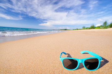 Fototapeta na wymiar Vacation concept. Blue sunglasses on the sea beach sand.