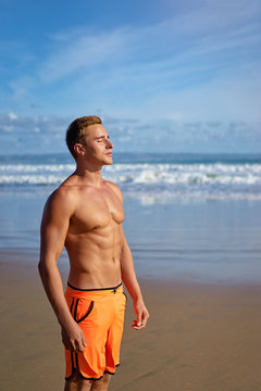 Enjoying the sea and sun. Handsome and strong young man tanning on the beach.