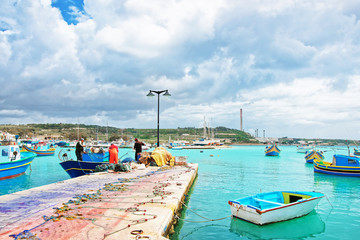 Fishermen on Luzzu colorful boat at Marsaxlokk Harbor on Malta