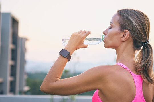Healthy lifestyle and technology. Close up of young pretty woman drinking water with digital smart tracker outdoors.