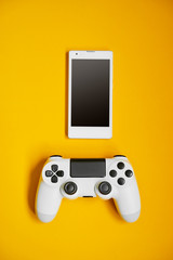 Computer game competition. Gaming concept. White cellphone and joystick on yellow background. © luengo_ua