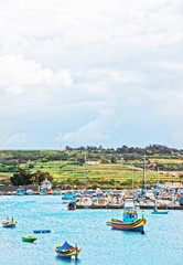 Fototapeta na wymiar Luzzu colorful boats at Marsaxlokk Harbor on Malta
