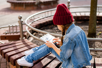 Stylish girl sitting with pills in hands, outdoors, back to photographer.