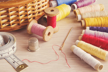 Colorful threads, needle and other accessories on the wooden table. Sewing works. Handmade. - obrazy, fototapety, plakaty