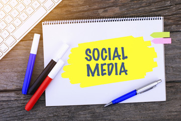Notebook with SOCIAL MEDIA Handwritten on wooden background and Modern Computer Keyboard. Top View Composition.