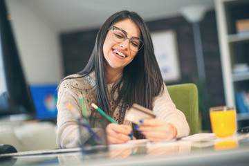 Businesswoman sitting at desk in office and holding credit card