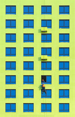 Workers install air conditioners on the wall of a newly built residential building