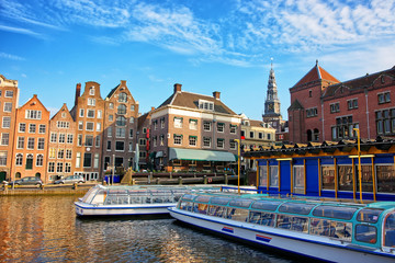 Naklejka premium Damrak Canal with boats and dancing houses in Amsterdam
