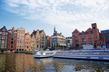 Damrak Canal with boats and dancing houses of Amsterdam
