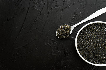 black caviar in white bowl  on black  background - obrazy, fototapety, plakaty